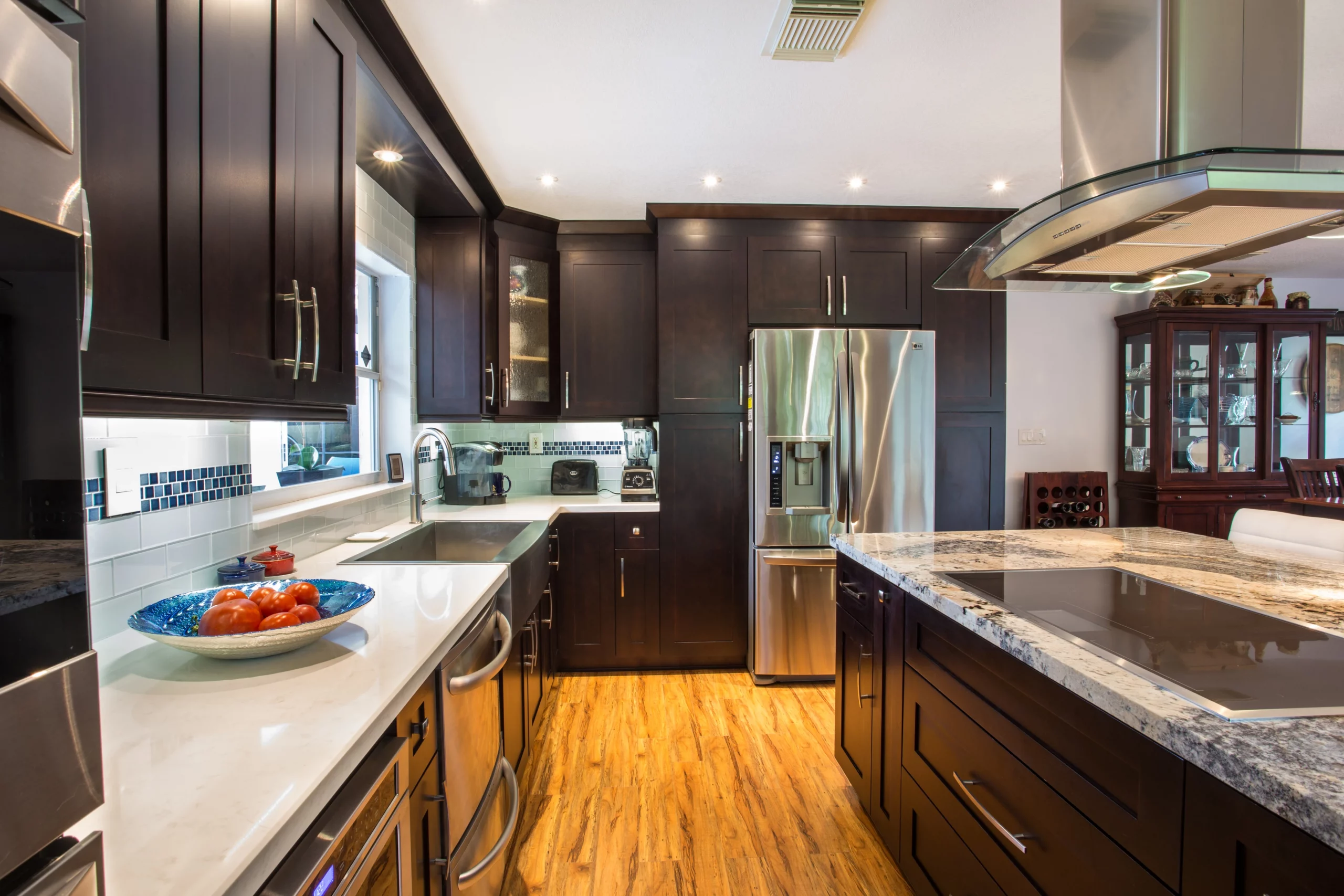 Modern kitchen with dark cabinets, stainless steel appliances, and granite island countertops.