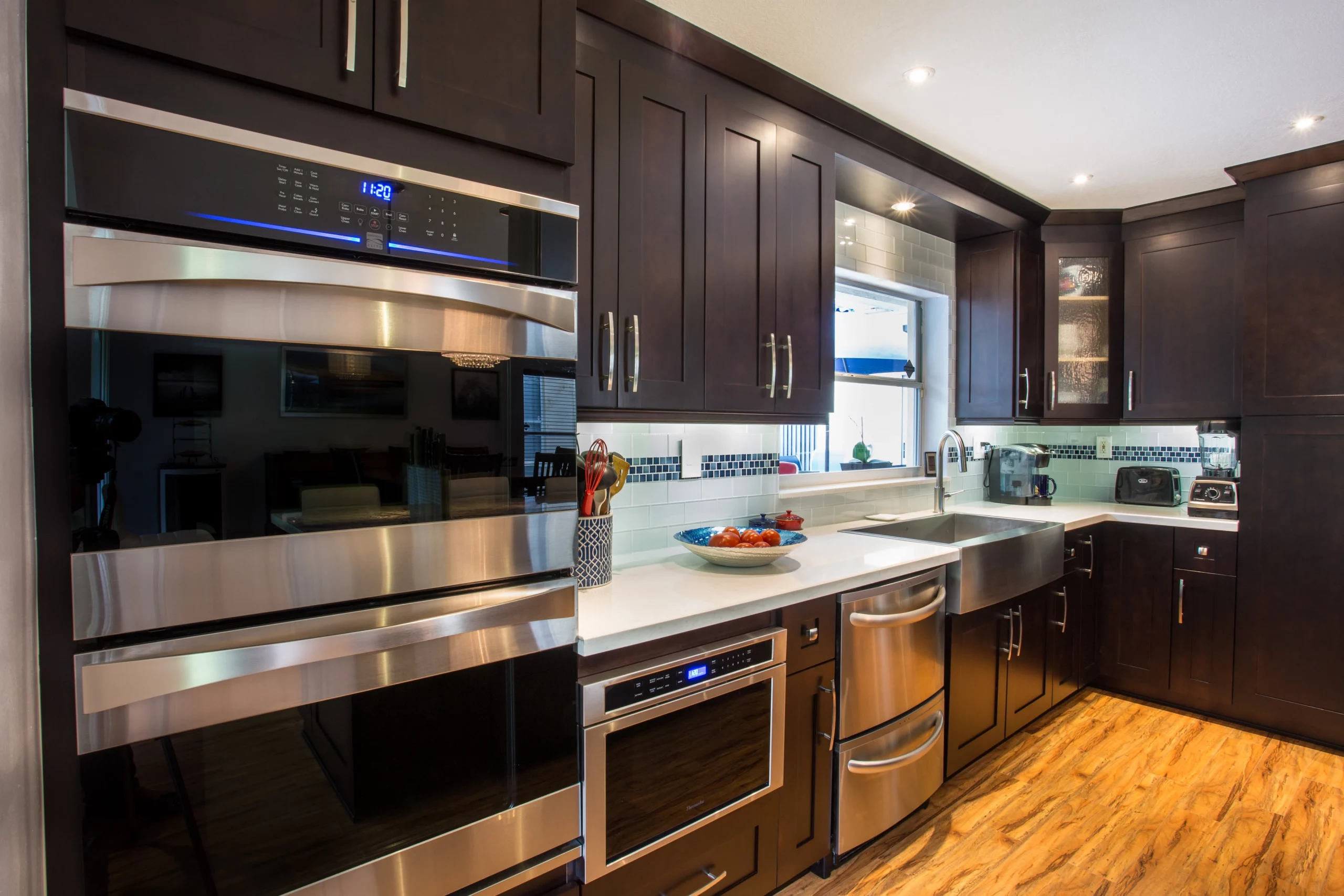 Modern kitchen remodeling featuring dark espresso cabinetry, stainless steel appliances, and light countertops.