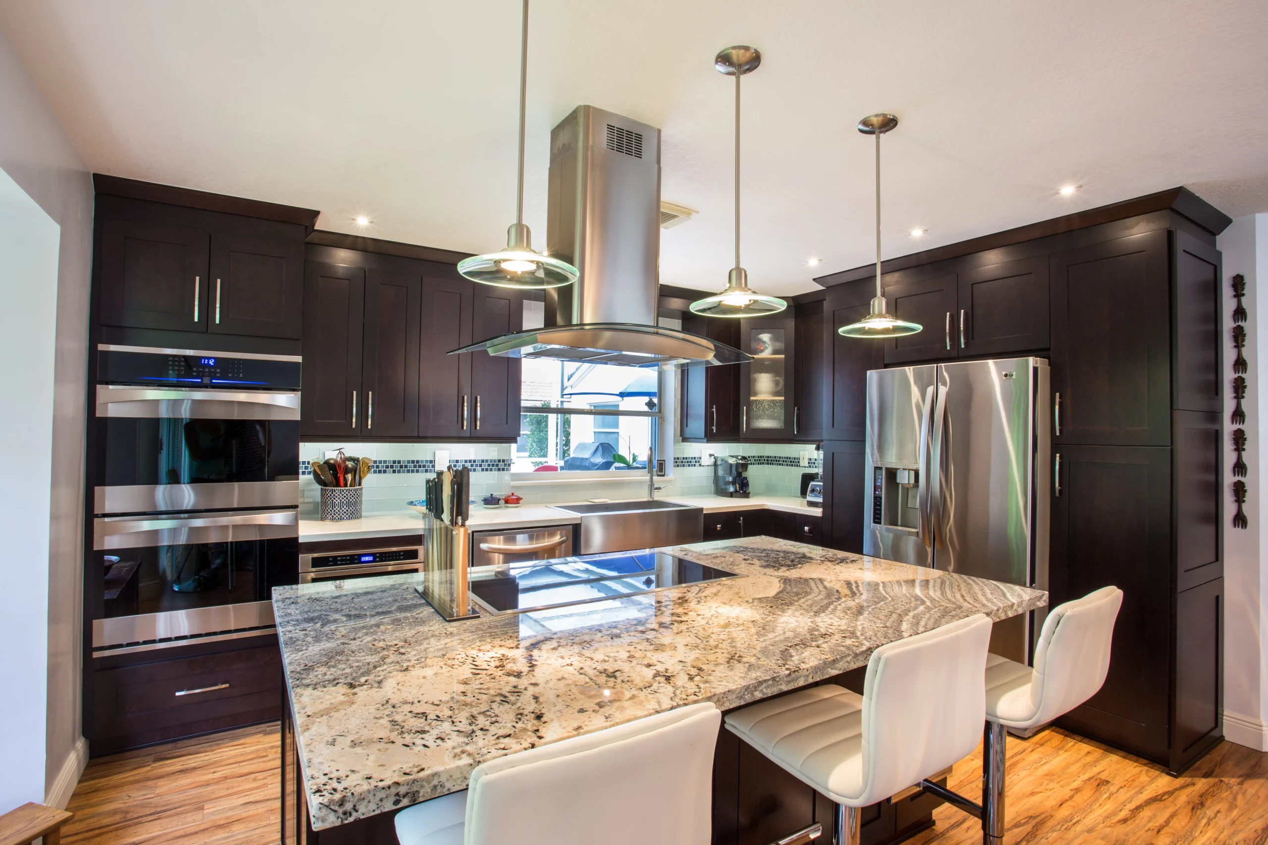 Modern kitchen remodeling featuring dark espresso cabinets, granite island, and stainless steel appliances.