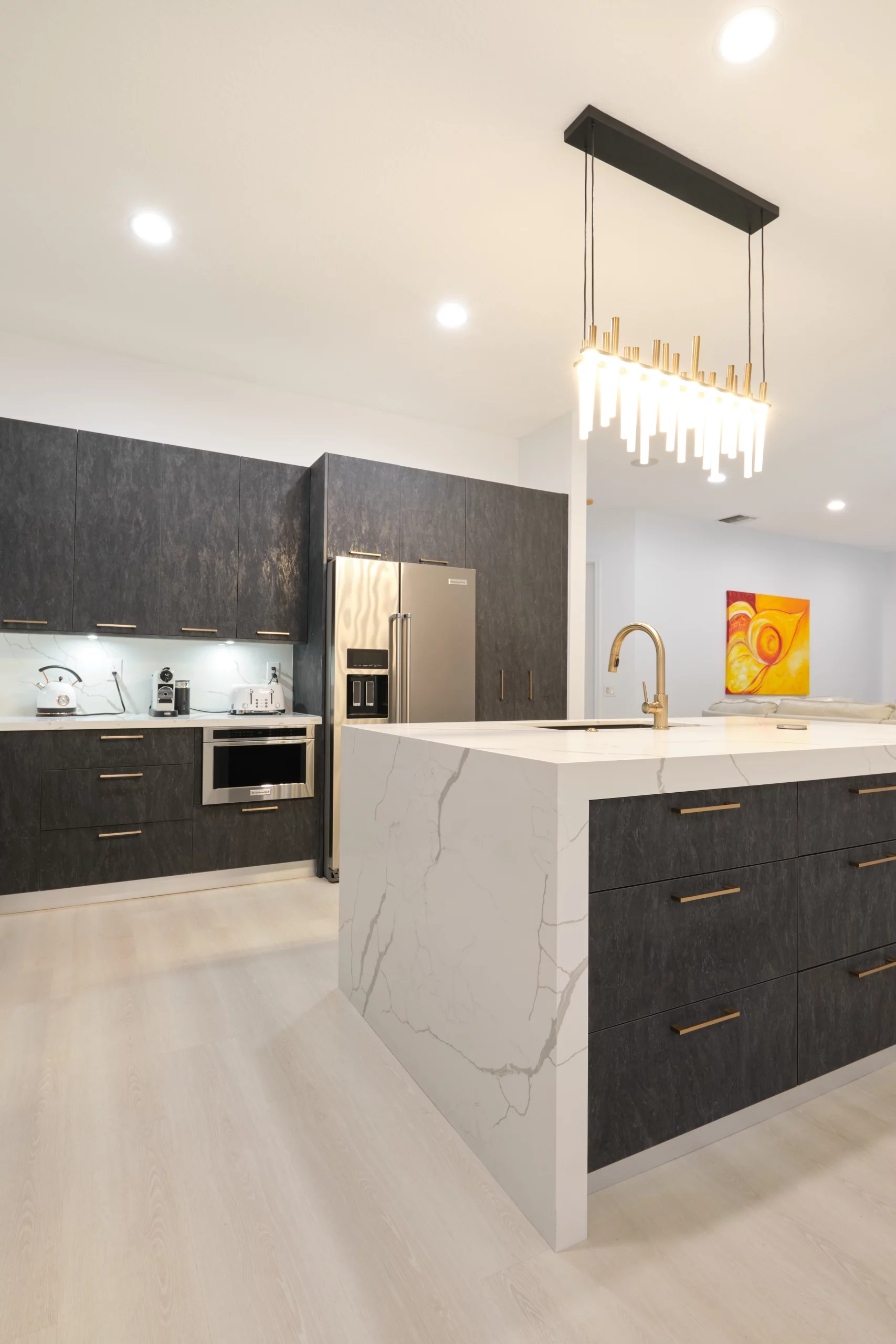 Modern kitchen remodeling with dark slate cabinets and a white quartz waterfall island.