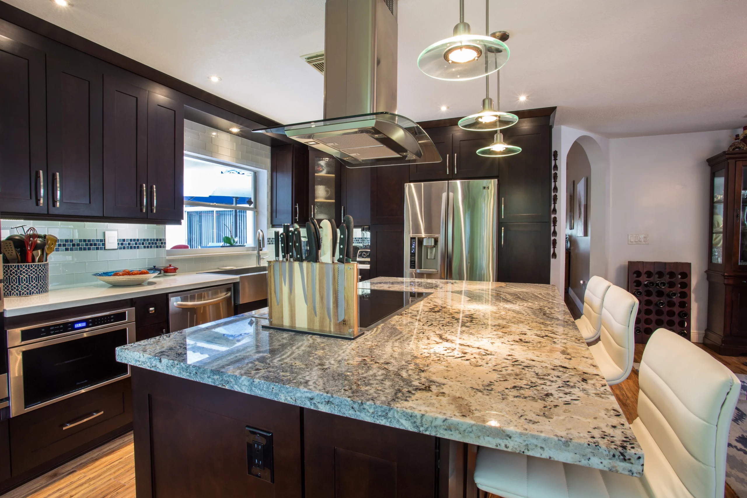 Contemporary kitchen remodeling featuring dark wood cabinets, granite island, and stainless steel appliances.