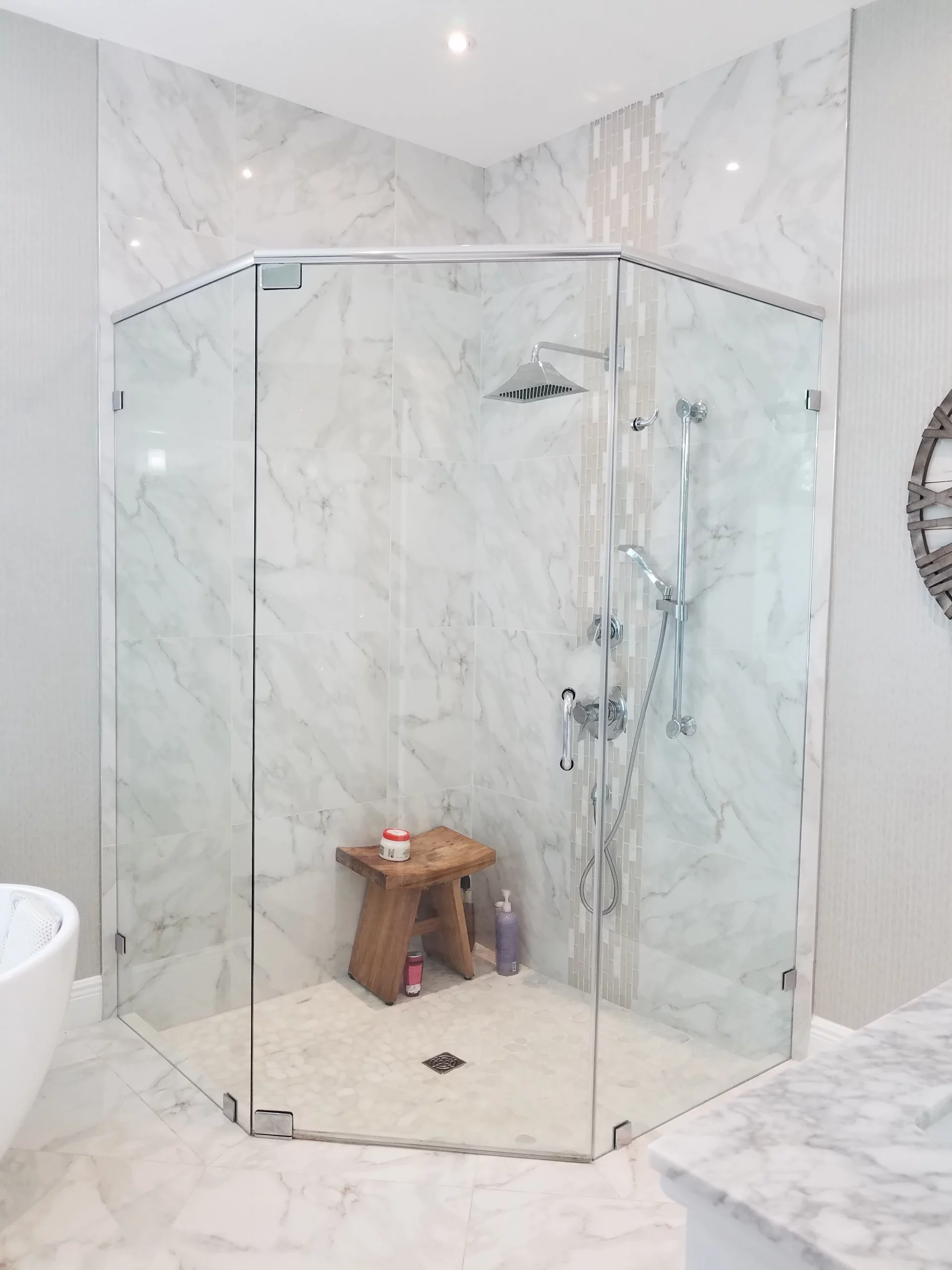 Luxury frameless glass shower enclosure with white marble tile in a bathroom remodeling project.