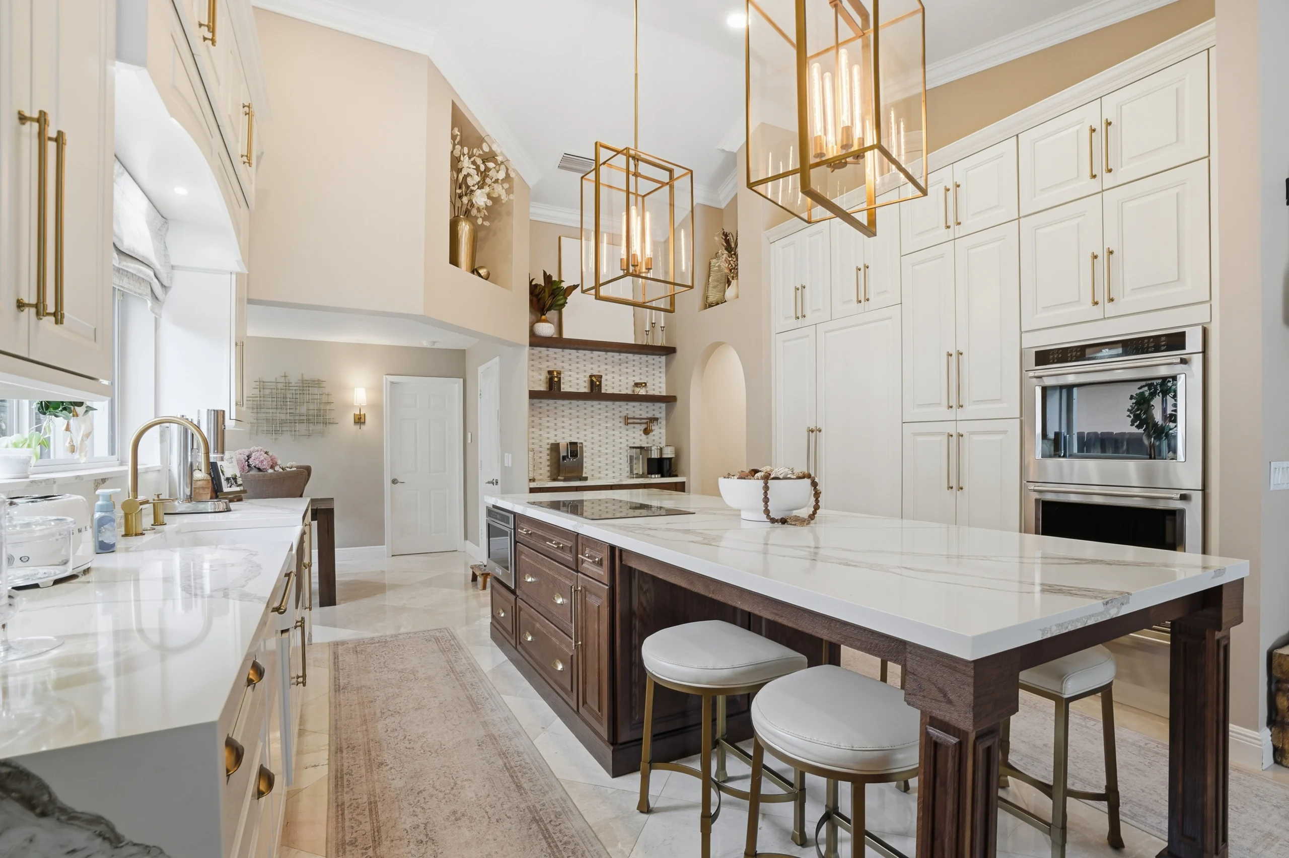 Luxury kitchen renovation in Plantation, Florida, featuring a dark wood island, white custom cabinetry, and brass lighting.