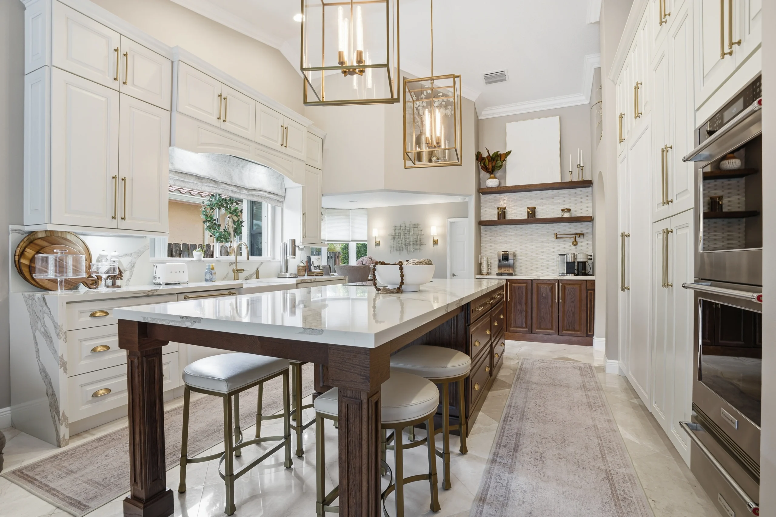 Luxury kitchen renovation in Plantation, FL featuring custom white and dark wood cabinetry with brass hardware and an island.