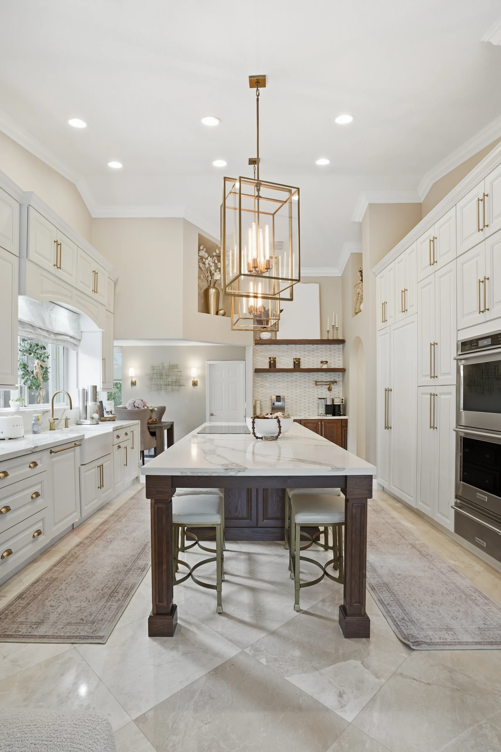 Luxurious white kitchen renovation in Plantation FL featuring a marble-topped dark wood island and custom cabinetry.