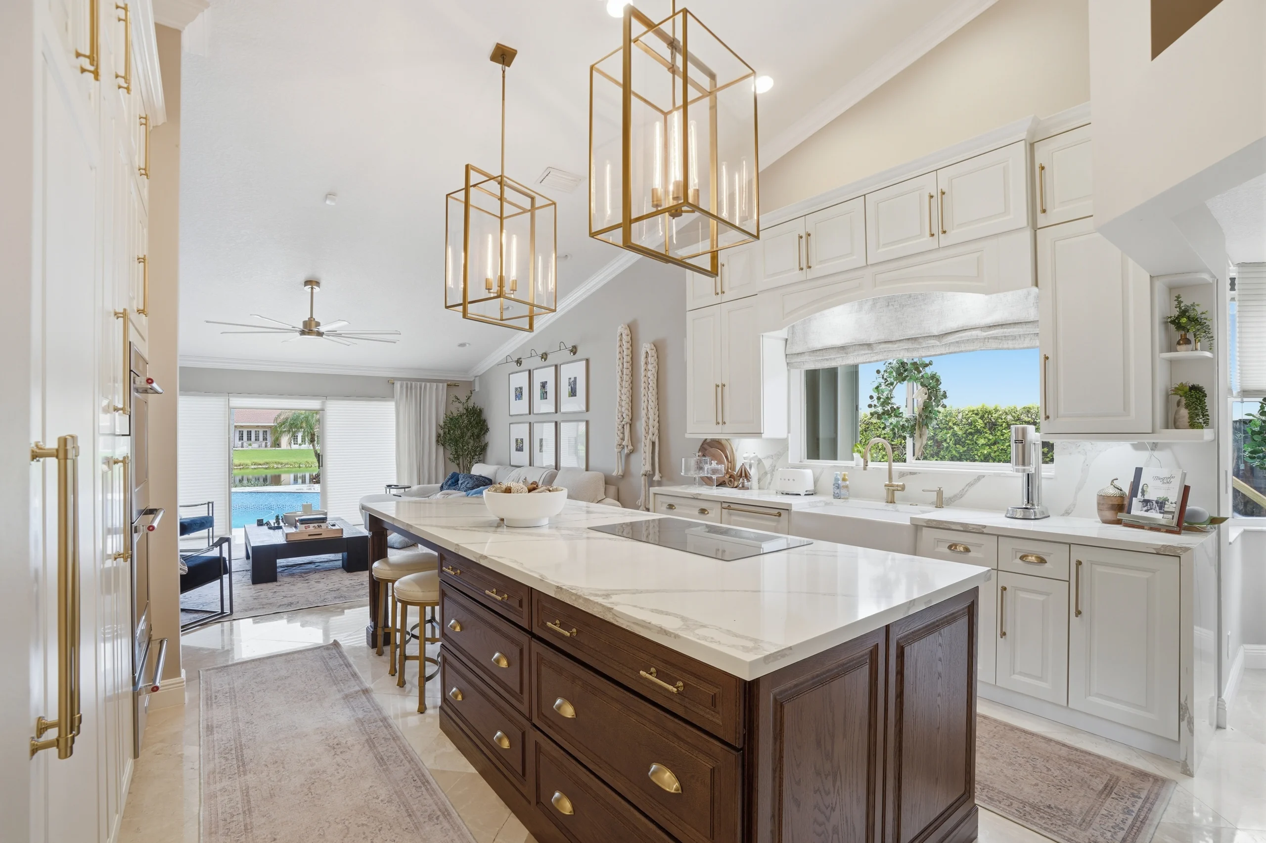 Luxury kitchen remodeling in Plantation FL featuring a dark wood island, white custom cabinetry, and elegant gold accents.