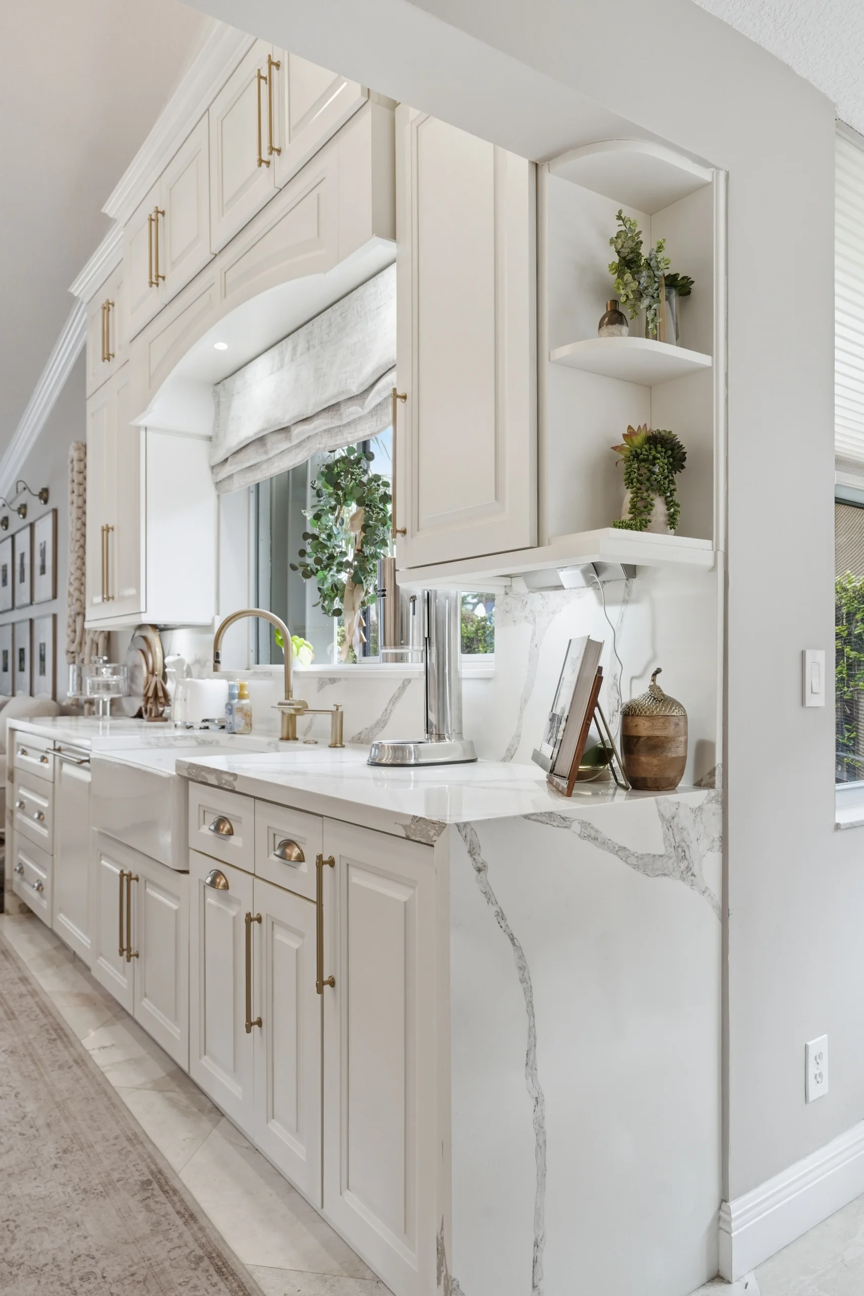 Elegant kitchen remodeling in Plantation FL featuring white custom cabinetry, gold hardware, and marble-veined countertops.