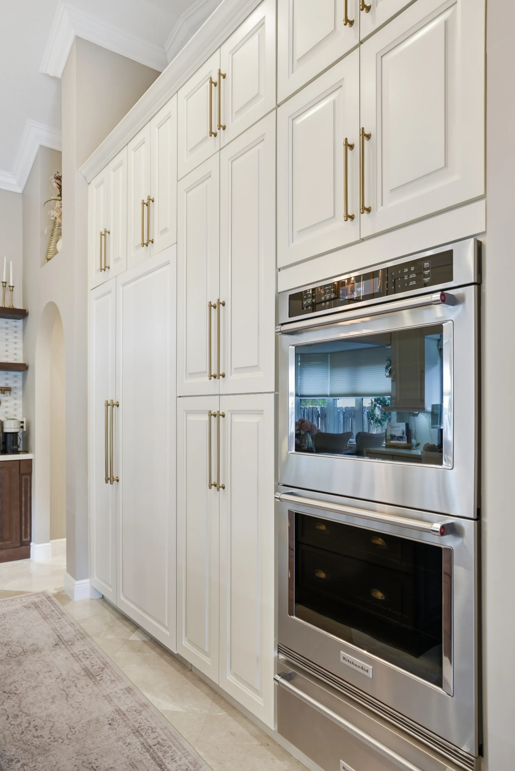 Custom white kitchen cabinetry with brass hardware and stainless steel wall ovens, part of a luxury remodel in Plantation.